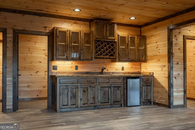 bar featuring wood walls, fridge, wood finished floors, and wood ceiling