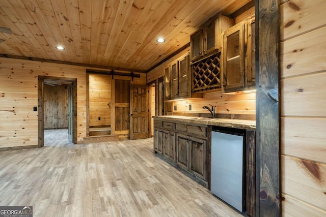 kitchen featuring dishwashing machine, a barn door, light wood-type flooring, and wood ceiling