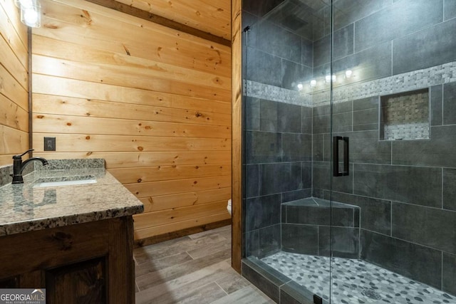 bathroom with a shower stall, vanity, and wooden walls