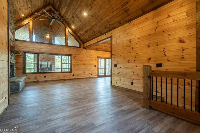 interior space featuring wooden walls, wood ceiling, wood finished floors, a fireplace, and high vaulted ceiling