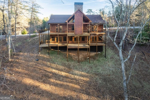 back of property with a deck, a chimney, and log veneer siding