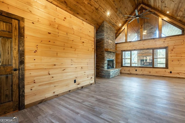 unfurnished living room featuring a fireplace, wood walls, wood finished floors, high vaulted ceiling, and wooden ceiling