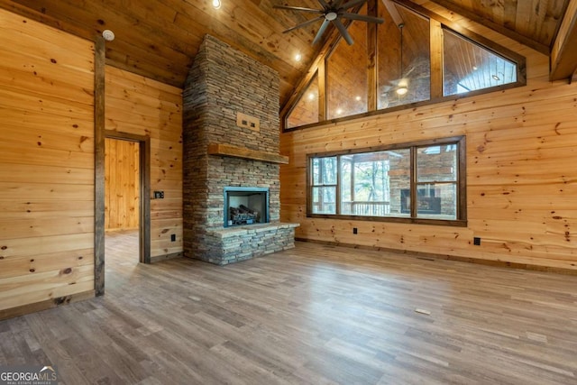 unfurnished living room with wooden ceiling, wood walls, a fireplace, wood finished floors, and a ceiling fan