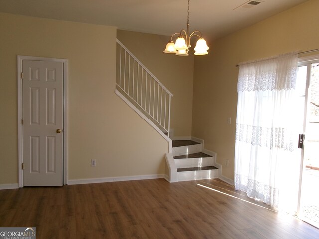 interior space featuring baseboards, a notable chandelier, visible vents, and wood finished floors