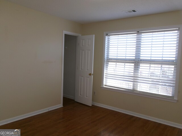 unfurnished room with wood finished floors, visible vents, and baseboards