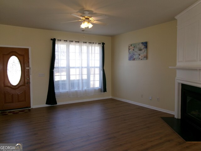 foyer with a fireplace with flush hearth, dark wood-type flooring, ceiling fan, and baseboards