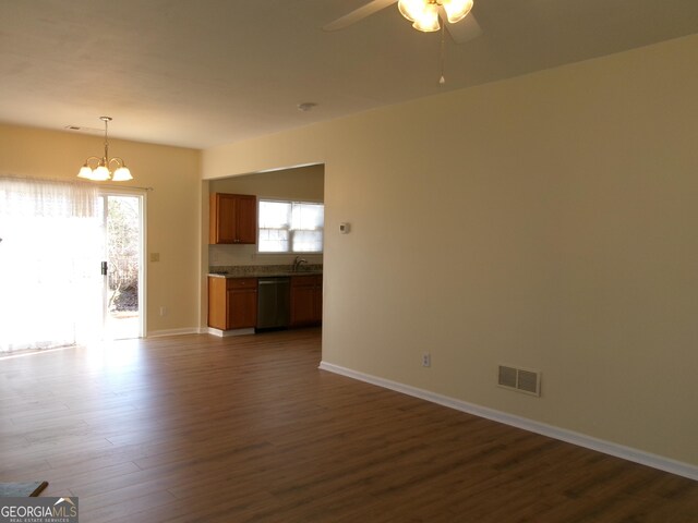 unfurnished living room featuring dark wood finished floors, visible vents, a sink, baseboards, and ceiling fan with notable chandelier