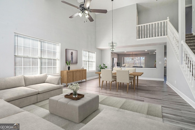 living room featuring ceiling fan, stairway, wood finished floors, and baseboards