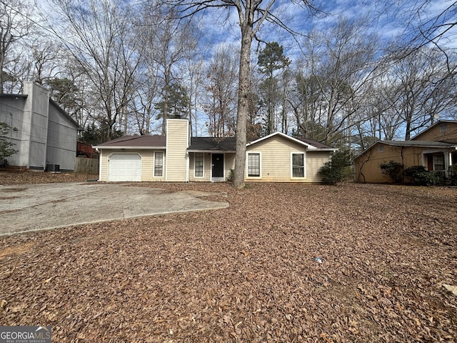 ranch-style home with a garage, a chimney, and aphalt driveway