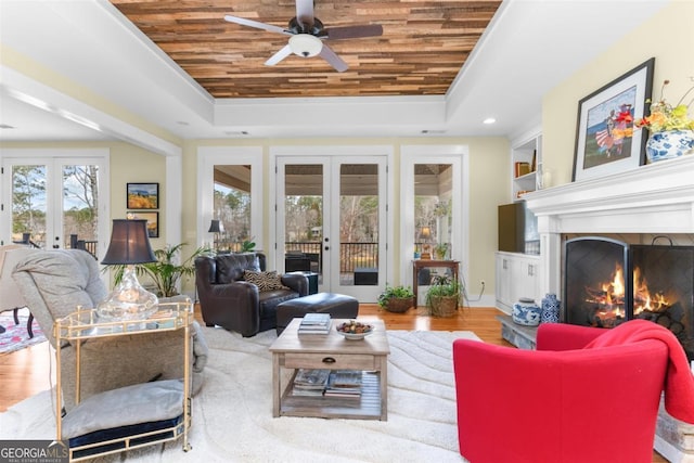 living area with wood ceiling, a tray ceiling, and french doors