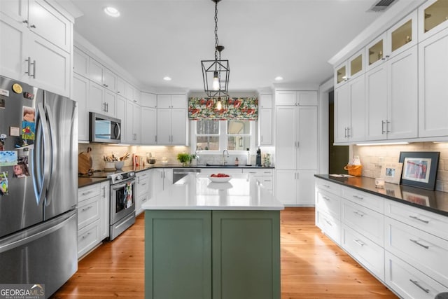 kitchen with appliances with stainless steel finishes, a center island, visible vents, and light wood-style flooring