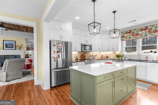 kitchen with a fireplace, a sink, white cabinetry, appliances with stainless steel finishes, and green cabinetry