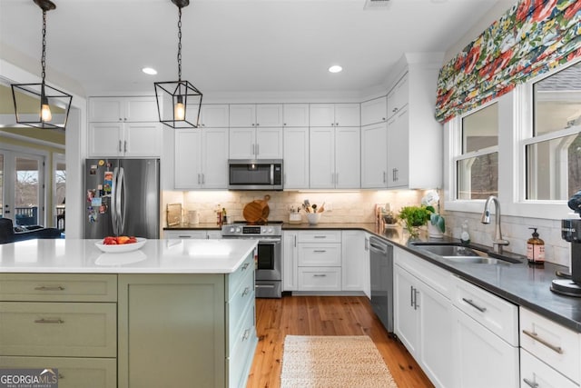 kitchen with stainless steel appliances, green cabinetry, a sink, and white cabinets