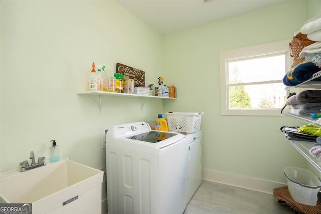 laundry area with laundry area, separate washer and dryer, a sink, and baseboards