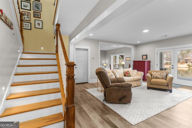 living room with a wealth of natural light, french doors, stairway, and wood finished floors