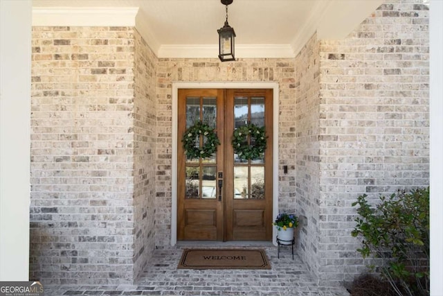 view of exterior entry featuring brick siding and french doors