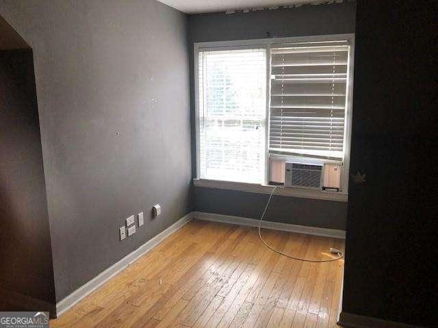 empty room featuring cooling unit, baseboards, and hardwood / wood-style floors