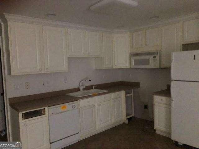 kitchen with white appliances, a sink, and white cabinetry