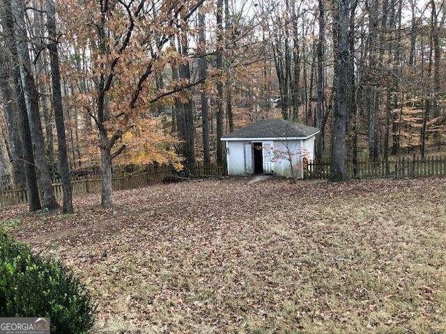 view of yard featuring an outbuilding, a forest view, fence, and a storage shed