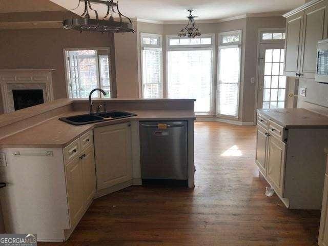 kitchen featuring crown molding, a sink, wood finished floors, a chandelier, and dishwasher