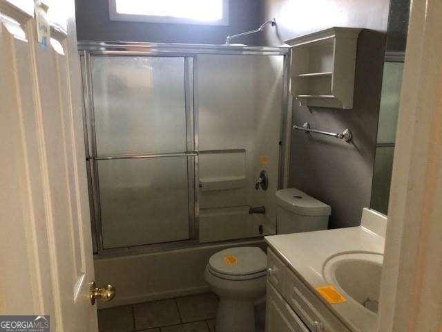 bathroom with toilet, vanity, bath / shower combo with glass door, and tile patterned floors