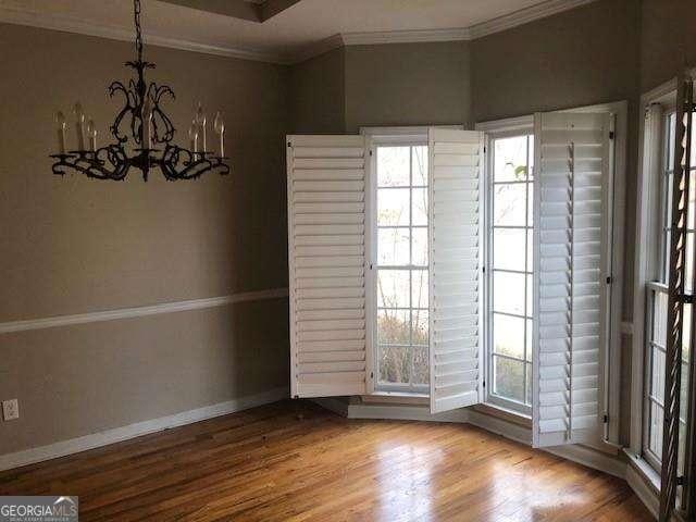 unfurnished dining area with a healthy amount of sunlight, baseboards, wood finished floors, and ornamental molding