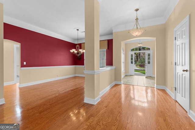 entrance foyer with arched walkways, light wood-style floors, baseboards, and an inviting chandelier