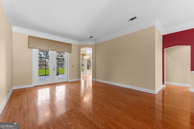 unfurnished room with arched walkways, wood finished floors, visible vents, and crown molding