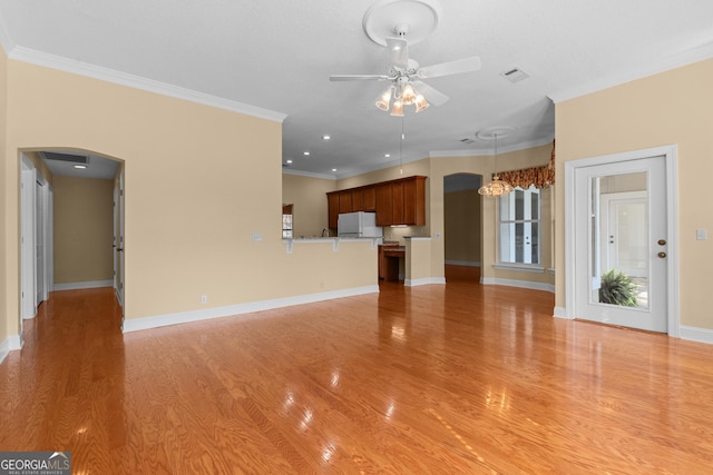 unfurnished living room with arched walkways, ornamental molding, a ceiling fan, and light wood-style floors