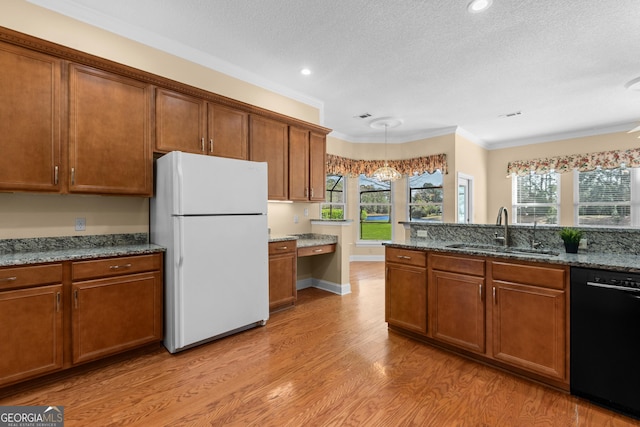 kitchen featuring black dishwasher, brown cabinetry, a sink, and freestanding refrigerator