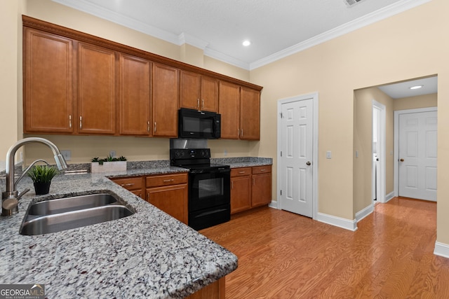 kitchen with black appliances, light wood-style floors, brown cabinets, and a sink