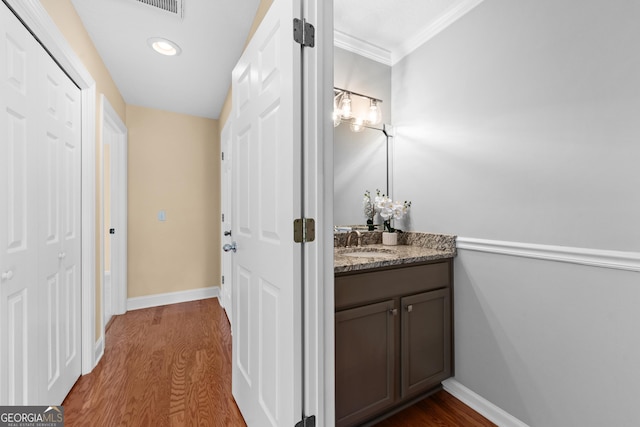 bathroom featuring crown molding, baseboards, wood finished floors, and vanity