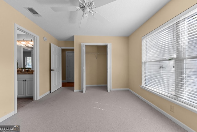 unfurnished bedroom featuring light colored carpet, a ceiling fan, baseboards, visible vents, and a closet