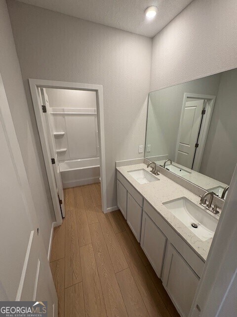 203 Park View Ln, Kingsland, GA 31548 - full bath featuring wood finished floors, a textured ceiling, double vanity, a bathtub, and a shower
