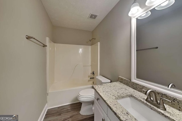 bathroom with visible vents, toilet, vanity, a textured ceiling, and wood finished floors