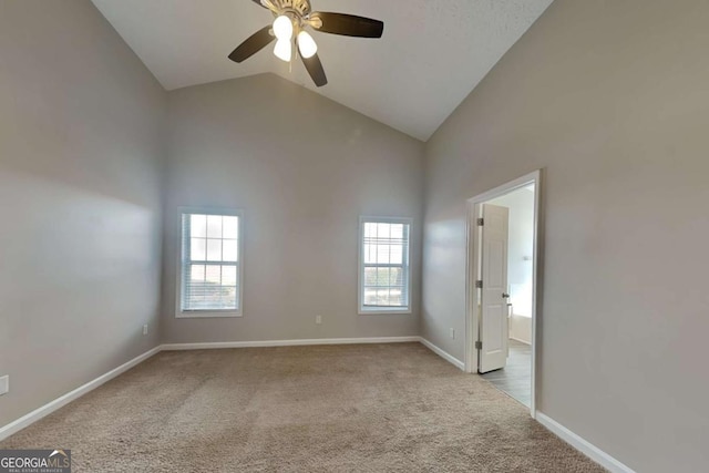 carpeted spare room with high vaulted ceiling, ceiling fan, and baseboards