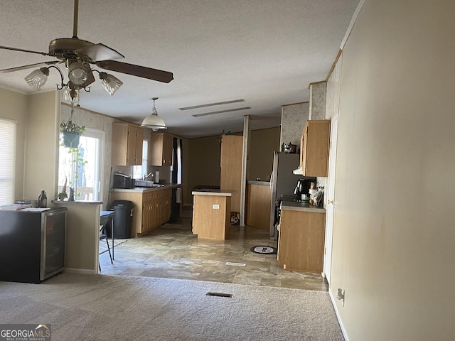 kitchen with light carpet, brown cabinetry, ornamental molding, a center island, and a textured ceiling