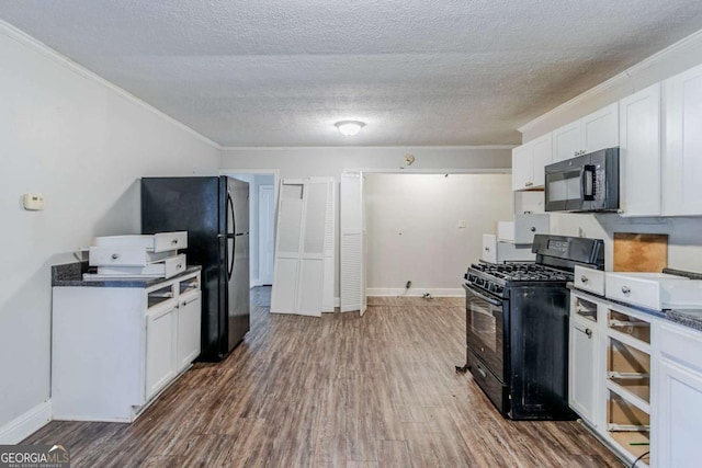 kitchen featuring black appliances, dark countertops, wood finished floors, and white cabinets