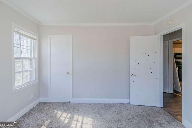 unfurnished bedroom featuring carpet floors, crown molding, and baseboards