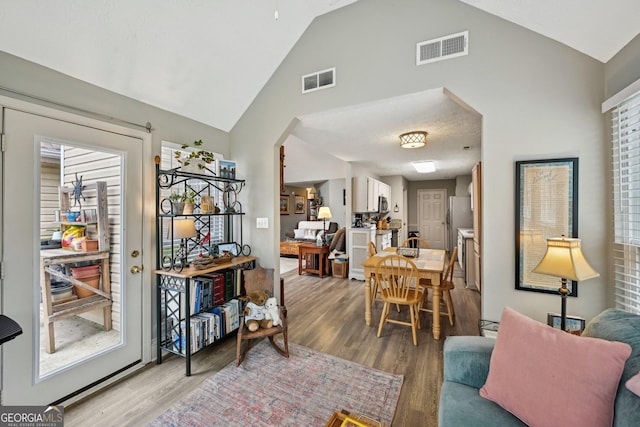 interior space featuring arched walkways, light wood-style flooring, and visible vents