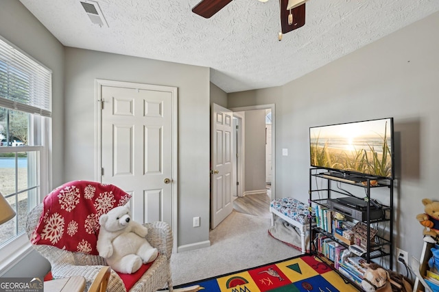 interior space featuring baseboards, visible vents, ceiling fan, a textured ceiling, and carpet flooring