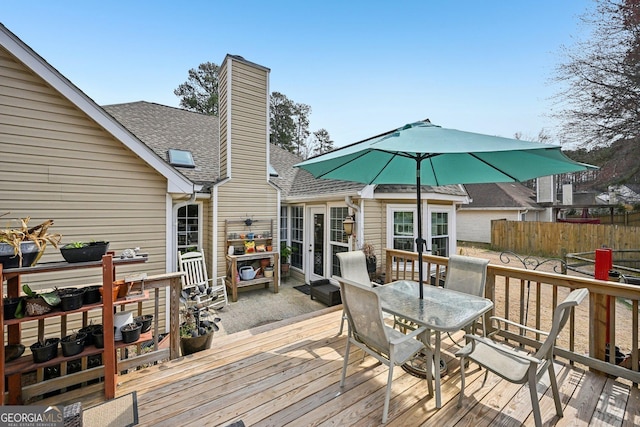 wooden deck featuring french doors, fence, and outdoor dining area