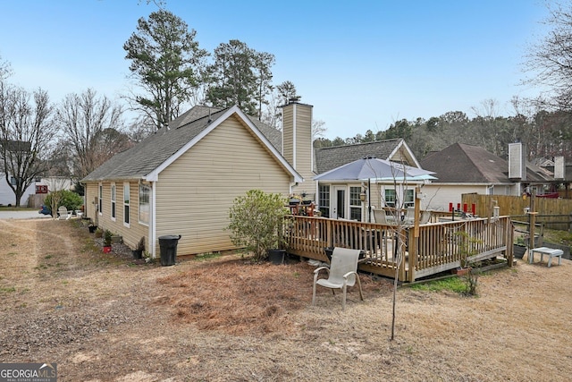 rear view of property featuring a chimney and a deck