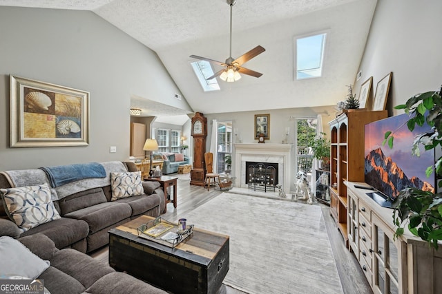 living room with a high end fireplace, a healthy amount of sunlight, ceiling fan, and a skylight