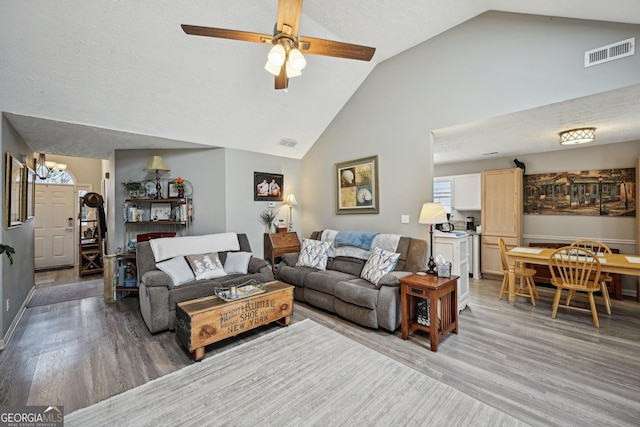 living area with a textured ceiling, light wood-type flooring, and visible vents