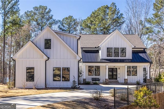 modern inspired farmhouse featuring metal roof, concrete driveway, roof with shingles, board and batten siding, and a standing seam roof