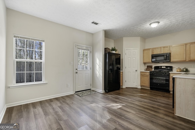 kitchen featuring dark wood-style flooring, light countertops, visible vents, black appliances, and baseboards