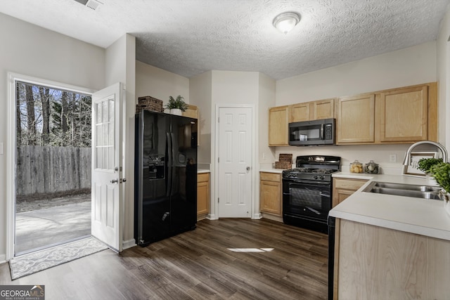 kitchen with dark wood-style floors, light countertops, light brown cabinets, a sink, and black appliances