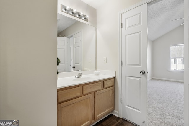 bathroom with lofted ceiling, baseboards, a textured ceiling, and vanity