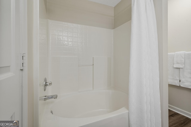 bathroom featuring wood finished floors and shower / bath combo with shower curtain